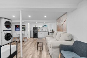 Una sala de estar moderna con un sofá, un banco y un comedor con sillas.