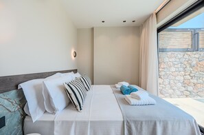 A hotel room with a bed, pillows, a blanket, and towels. - Metatulia Villa 8 – Private Pool, Jacuzzi & Views (Plakias)