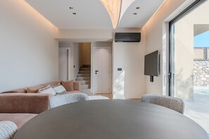 Ein modernes Wohnzimmer mit einer Couch, einem runden Tisch und einem an der Wand befestigten Fernseher.