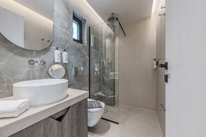 Ein modernes Badezimmer mit einem großen Waschbecken, einem Spiegel und einer Duschkabine.
