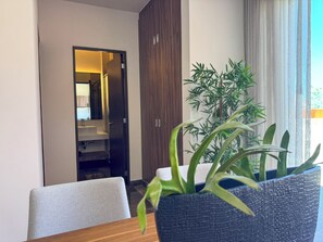 A hotel room with a wooden wardrobe, a bathroom visible through an open door, and a potted plant on a table. - 3BR Tulum Penthouse with Private Pool & Jungle Views (Tulum)