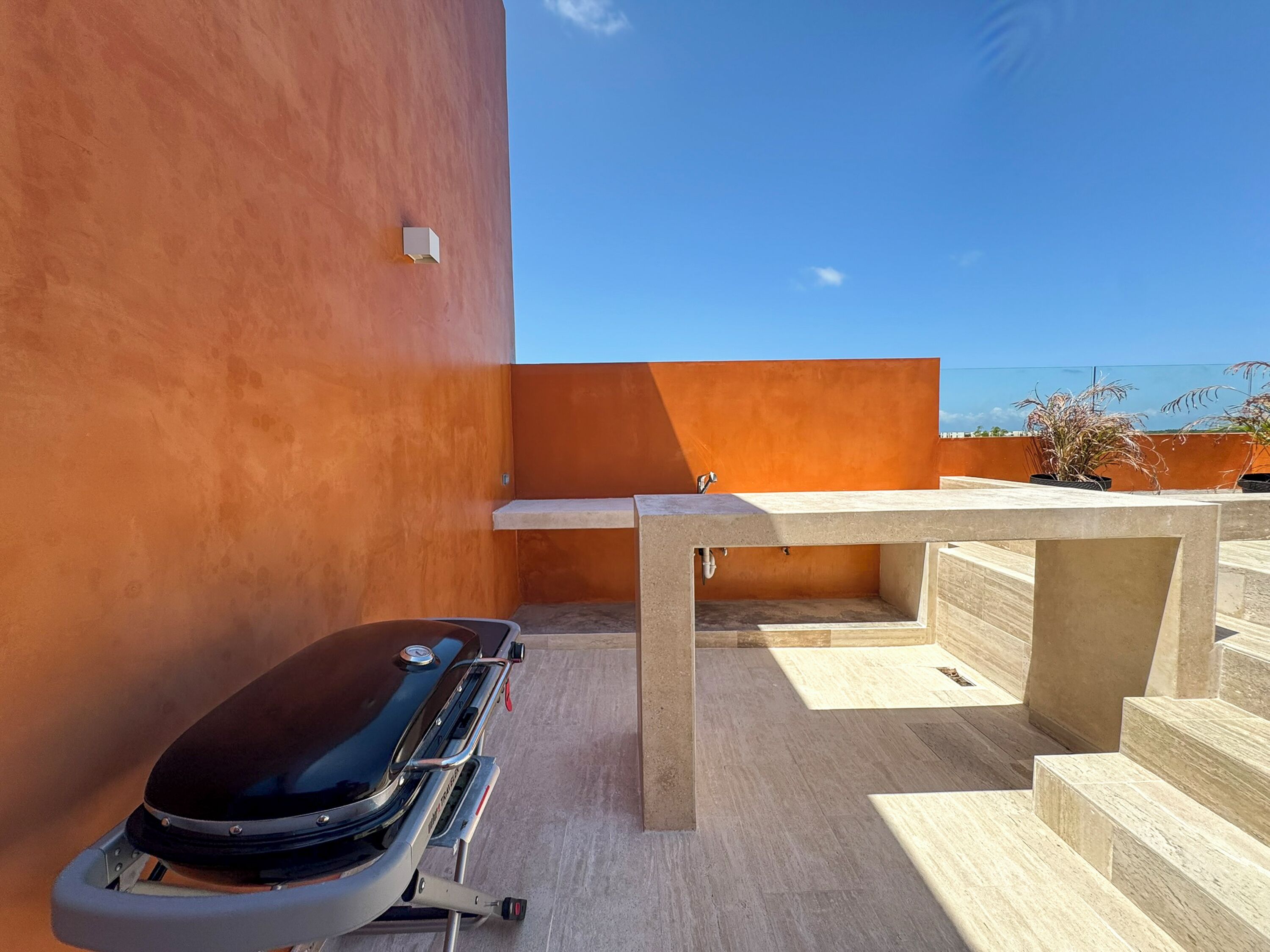 Une terrasse sur le toit équipée d’un barbecue, d’une table et offrant une vue sur l’océan.