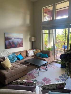 A living room with a sofa set, a coffee table, and a painting on the wall. - Gorgeous executive condo (Surrey)
