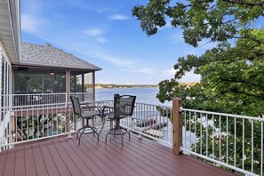 A covered outdoor deck with a table and chairs, overlooking a body of water. - Osage Beach, 4b, Private cove, sleeps 10 (Osage Beach)