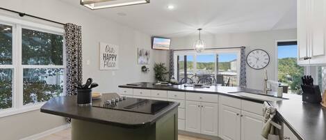 A modern kitchen with a central island, a large window, and a view of the outdoors.
