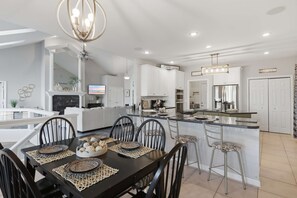 A modern kitchen with white cabinetry, a central island, and a dining area with a black table and chairs. - Osage Beach, 4b, Private cove, sleeps 10 (Osage Beach)