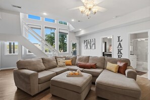 A spacious living room with a sectional sofa, a coffee table, and a staircase leading to an upper level. - Osage Beach, 4b, Private cove, sleeps 10 (Osage Beach)