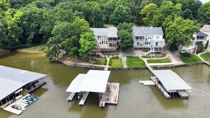 A lakeside property with multiple docked boats, a well-maintained lawn, and a large house with a balcony. - Osage Beach, 4b, Private cove, sleeps 10 (Osage Beach)