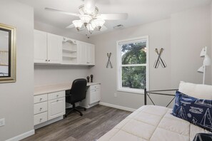 A bedroom with a bed, a desk, and a chair. There is a window with a view of trees. - Osage Beach, 4b, Private cove, sleeps 10 (Osage Beach)