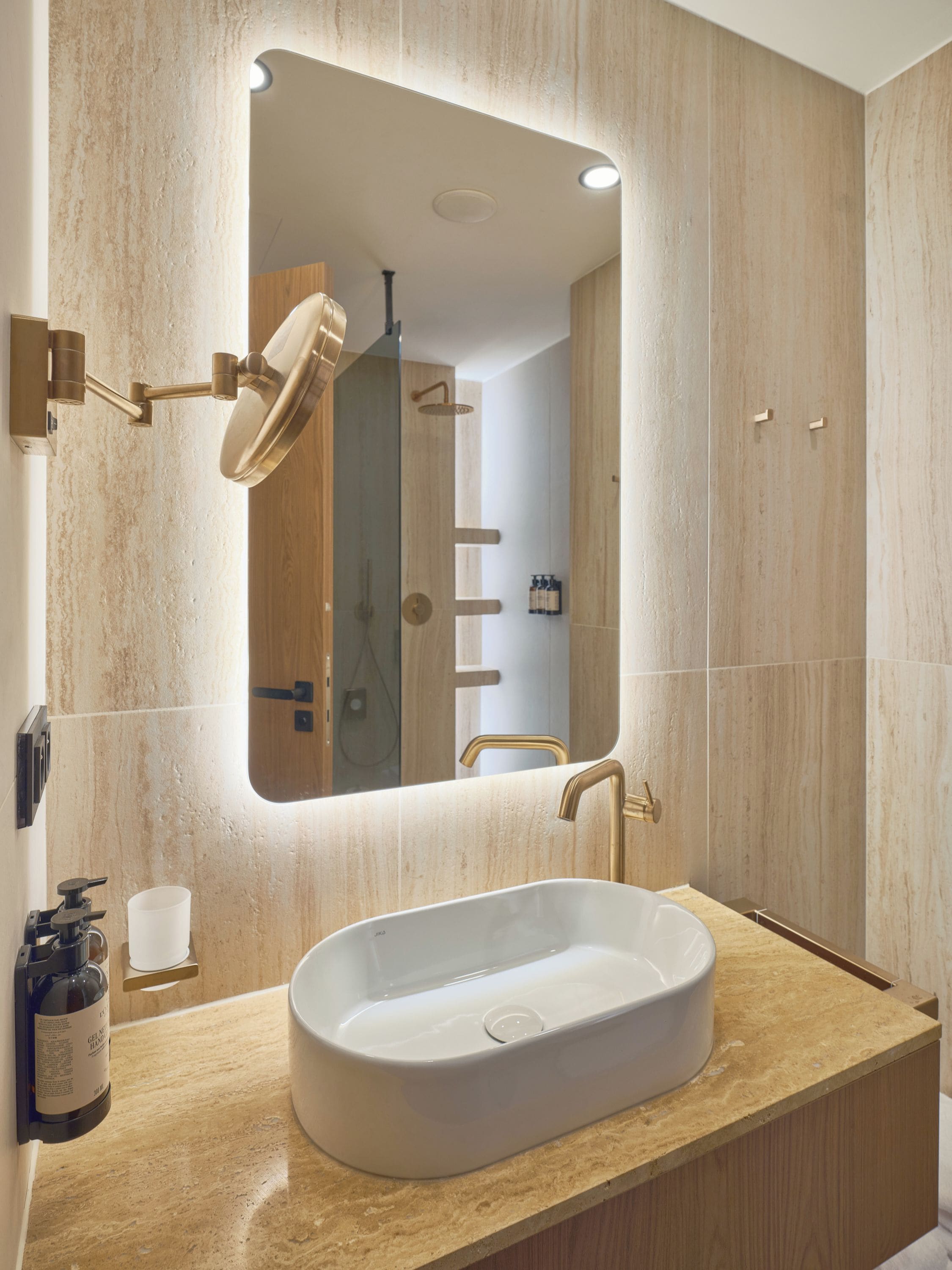 Un baño moderno con un espejo grande, un lavamanos blanco y una zona de ducha.