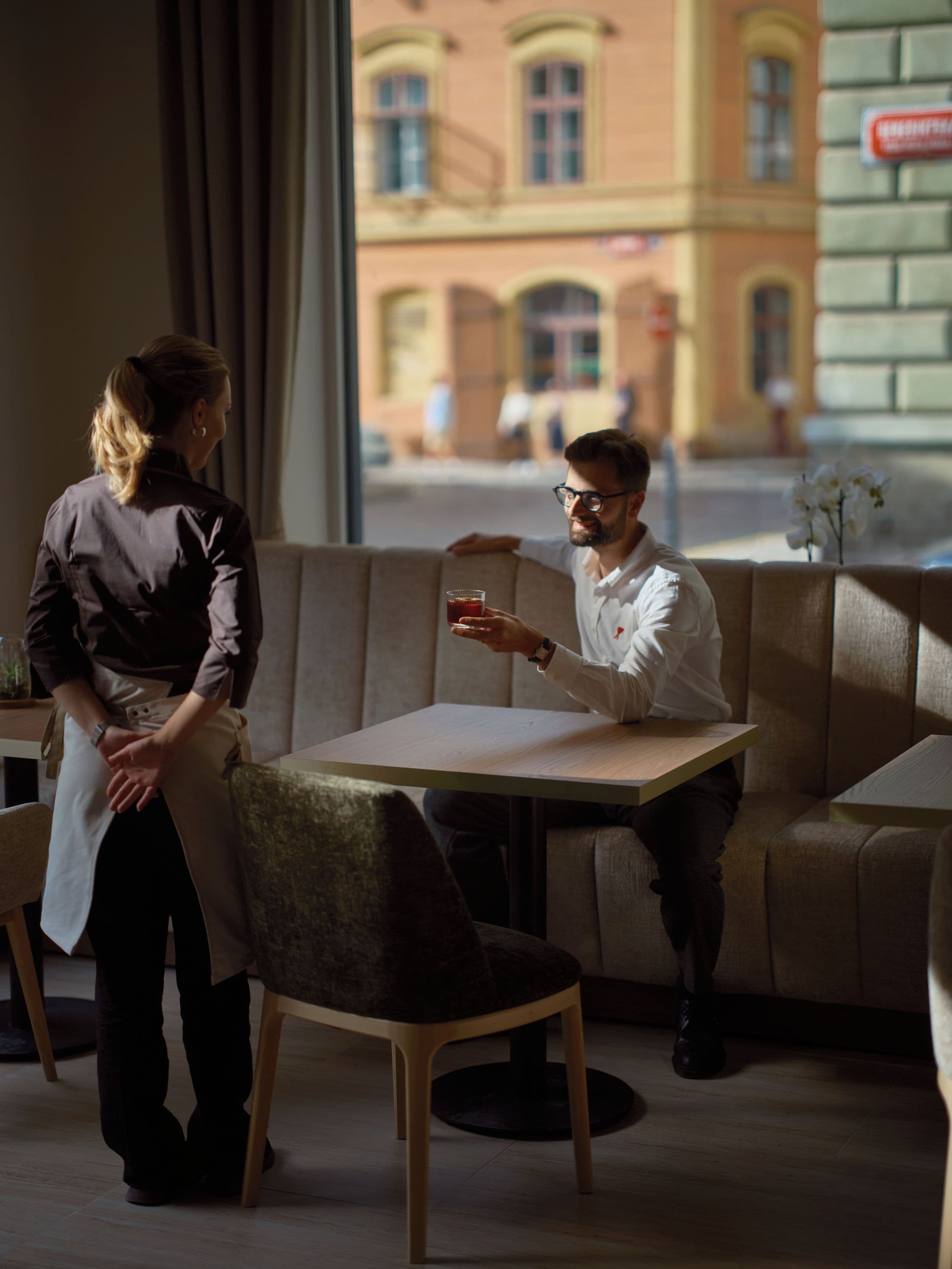 Een café interieur met een tafel, stoelen en uitzicht op de straat.