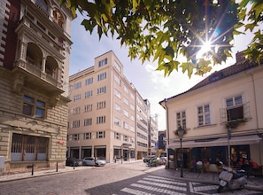 Vista de una calle con edificios, un paso de peatones y vehículos estacionados.