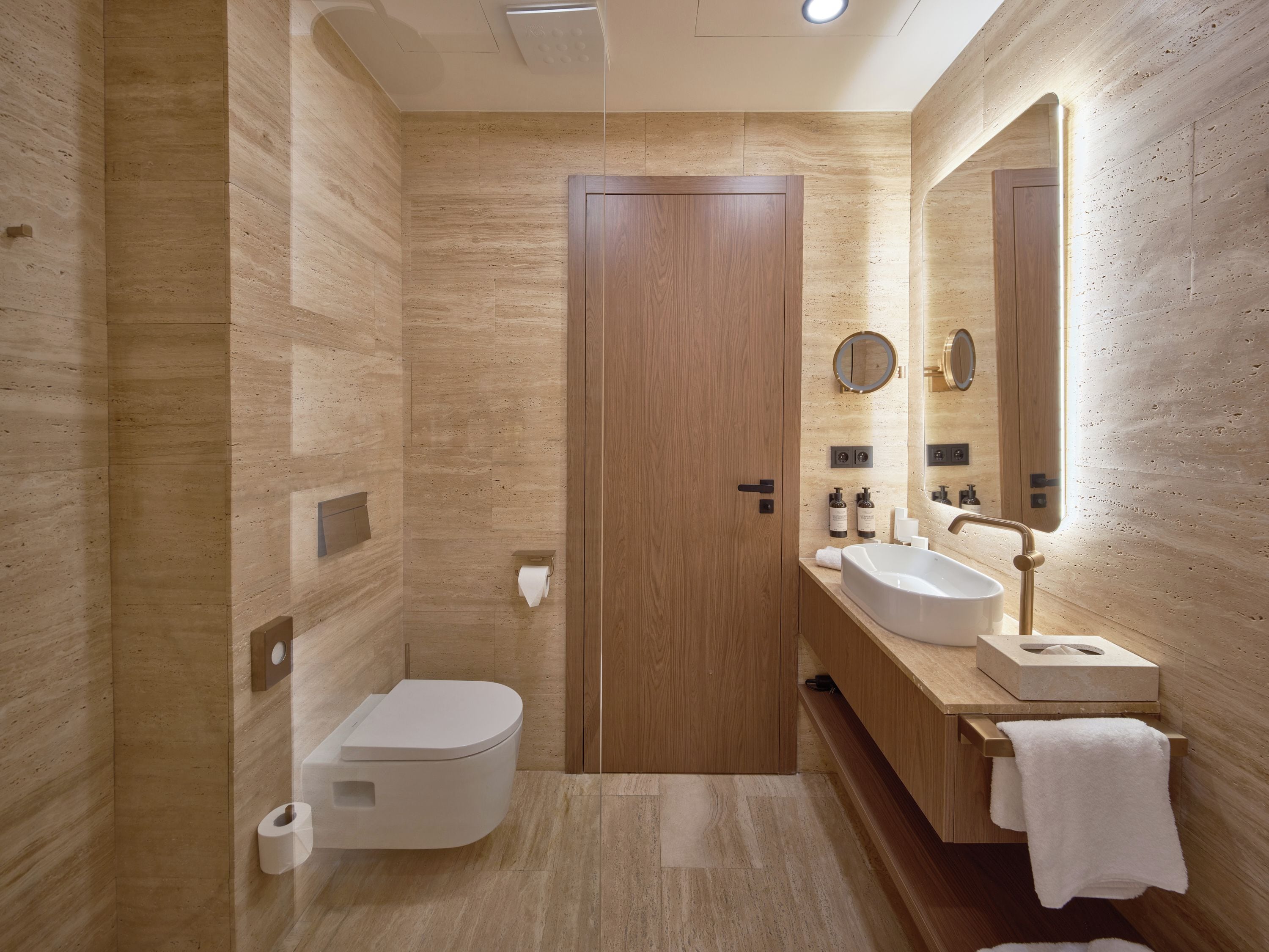 Un bagno moderno con una porta in legno, un water, un lavandino e uno specchio.
