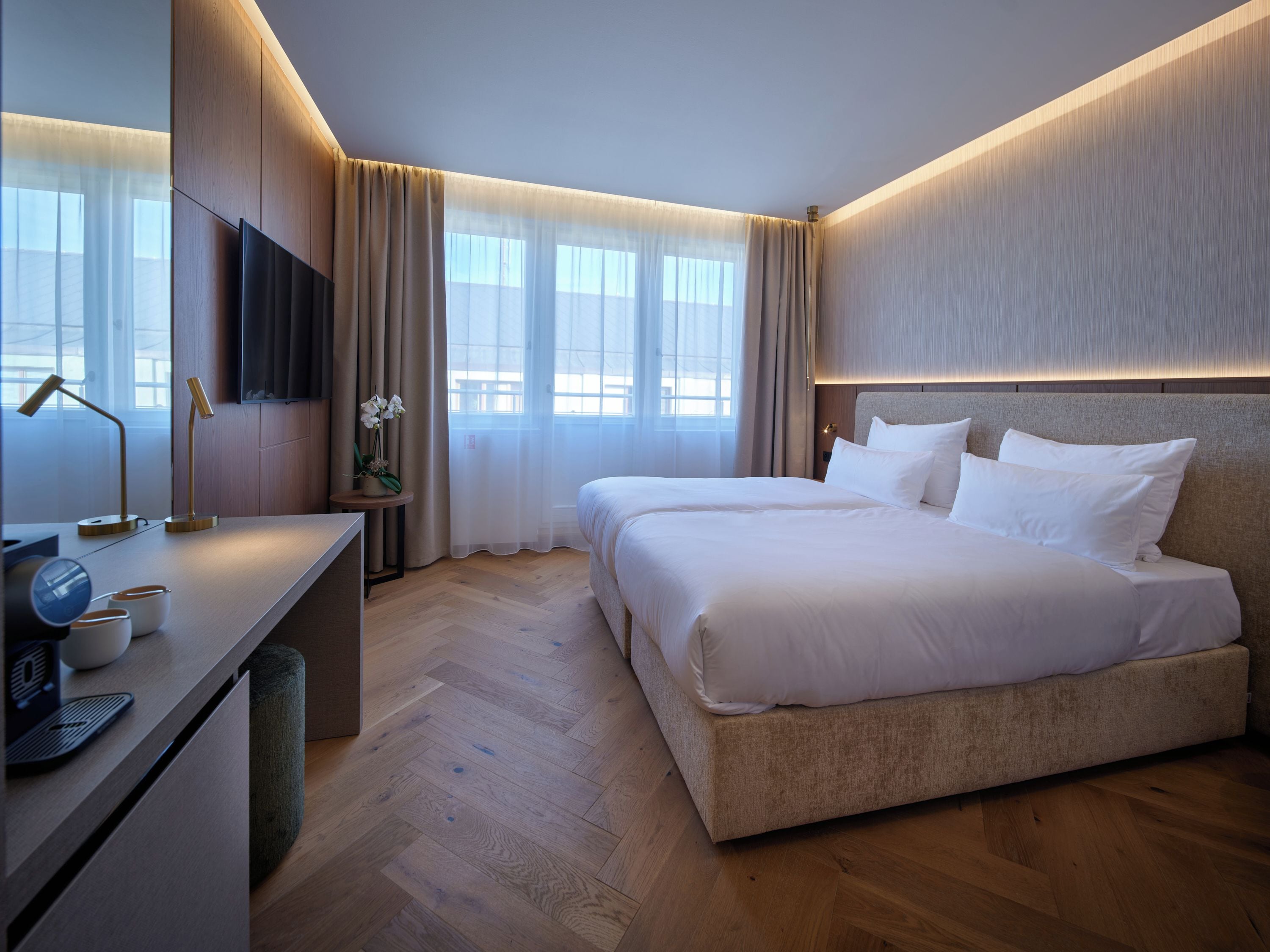 Una habitación de hotel moderna con una cama grande, un escritorio con lámpara y un televisor.