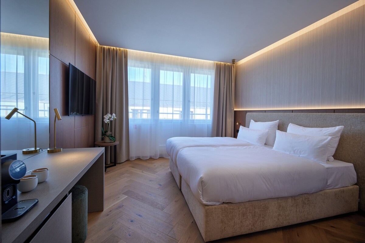 Una habitación de hotel moderna con una cama grande, un escritorio con lámpara y un televisor.