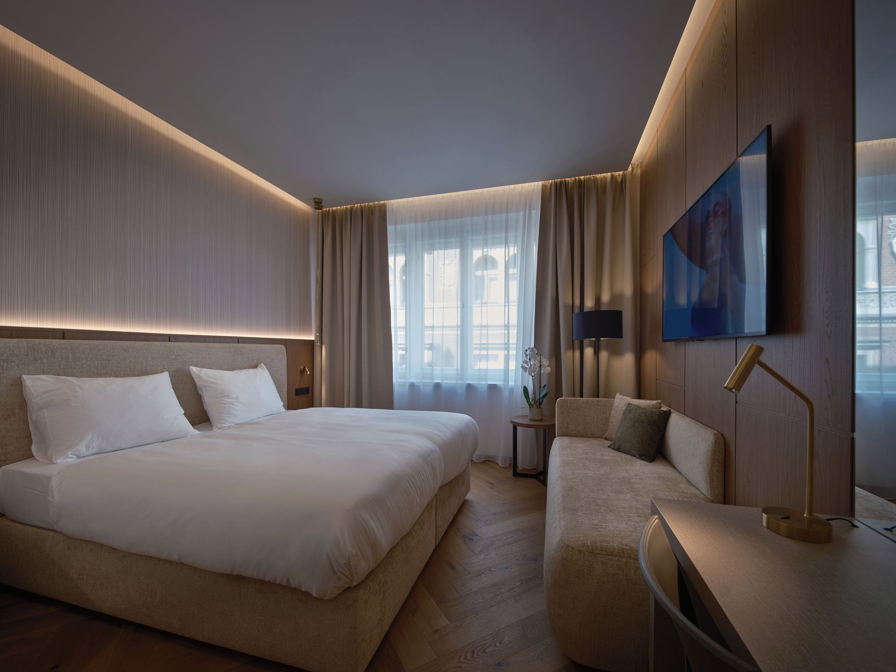 Une chambre d’hôtel avec un grand lit, un canapé, un bureau et une télévision.