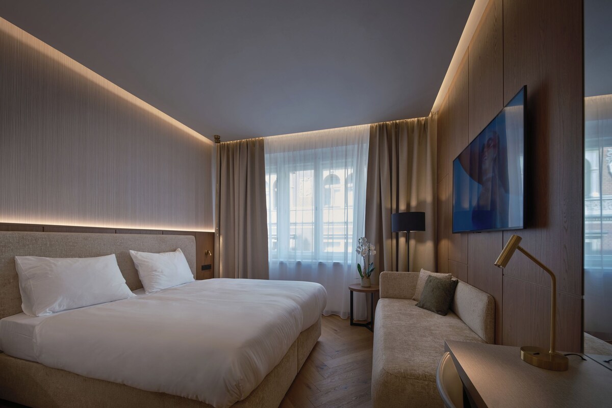 Habitación de hotel con una cama grande, un sofá, un escritorio y un televisor.