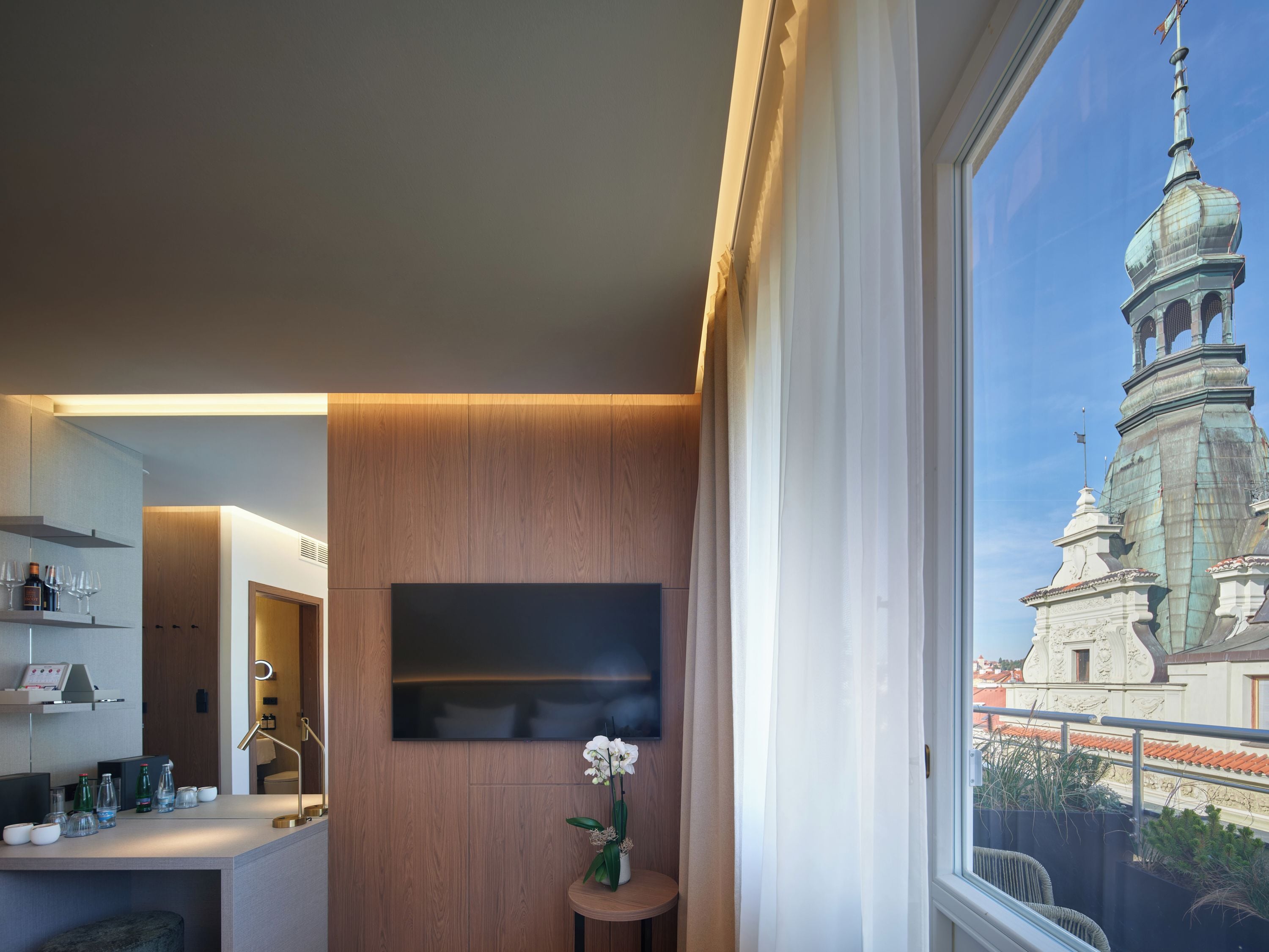 Ein modernes Interieur mit einem großen Fenster, einer Holzpaneelwand und Blick auf einen historischen Turm.