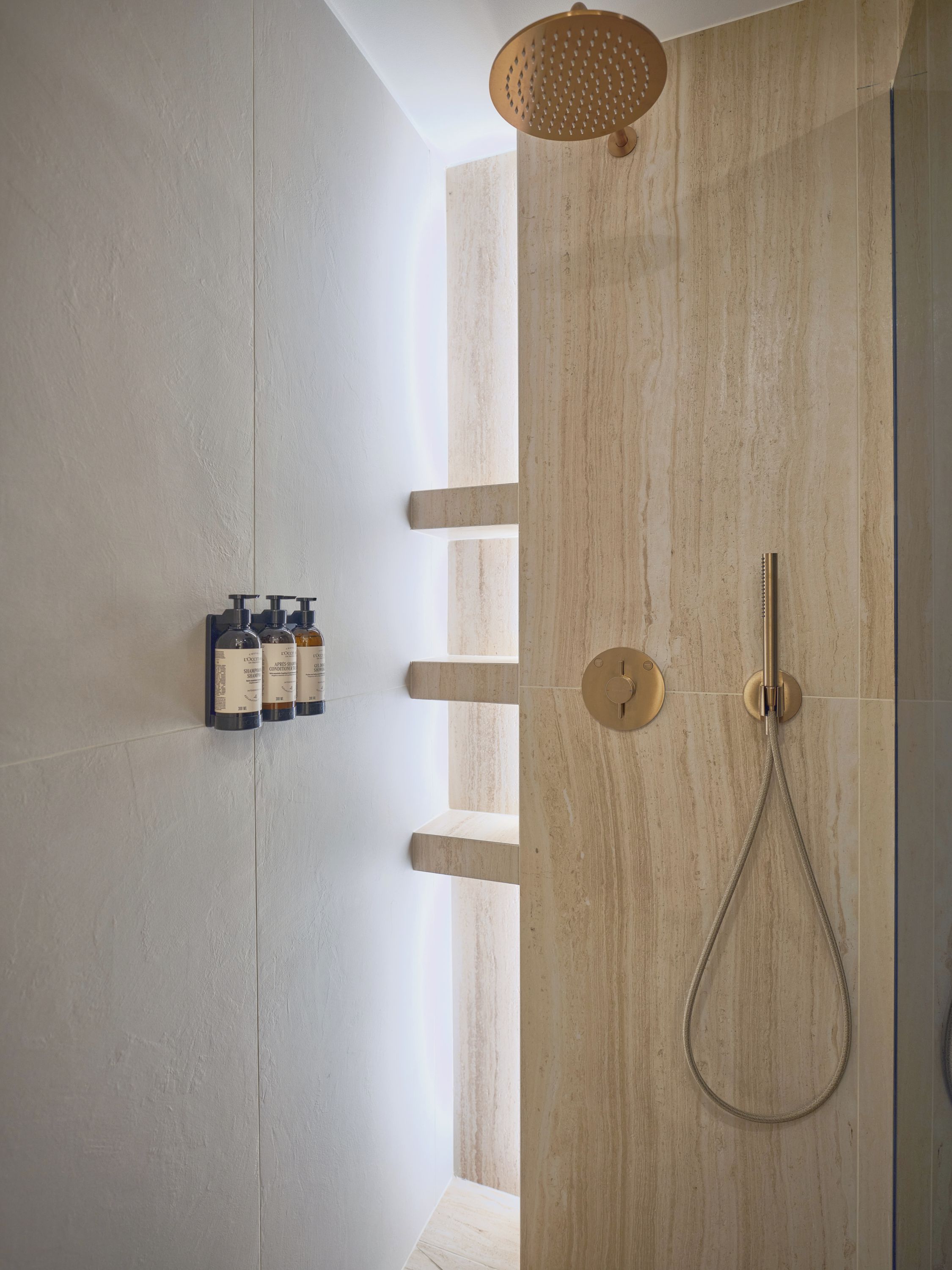 A modern bathroom with a shower, a towel rack, and shampoo bottles.