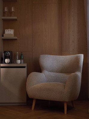 Una sala de estar moderna con un sofá texturizado, un mueble de madera con una radio y una mesita con una botella y vasos.