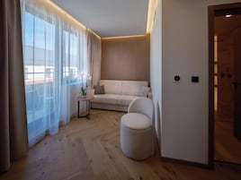 Una sala moderna con un sofá, un reposapiés y una pequeña mesa con un florero.