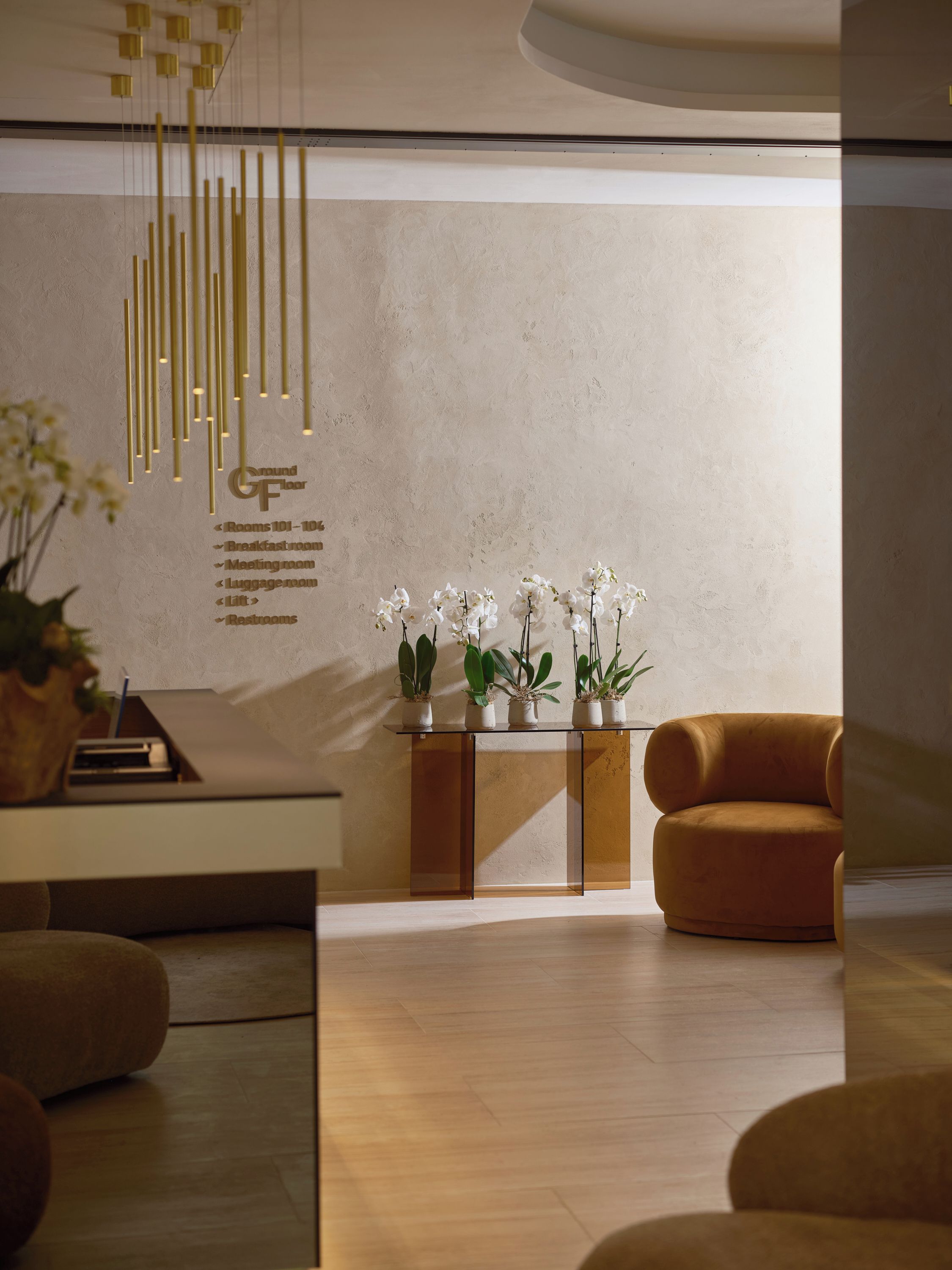 Una moderna recepción con diseño minimalista, que presenta un mostrador de recepción, un área de estar con un sofá, una mesa de vidrio con plantas en macetas y un cartel en la pared que enumera los servicios.