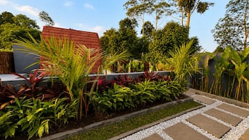 A garden with a variety of plants, a pathway, and a building with a red roof.