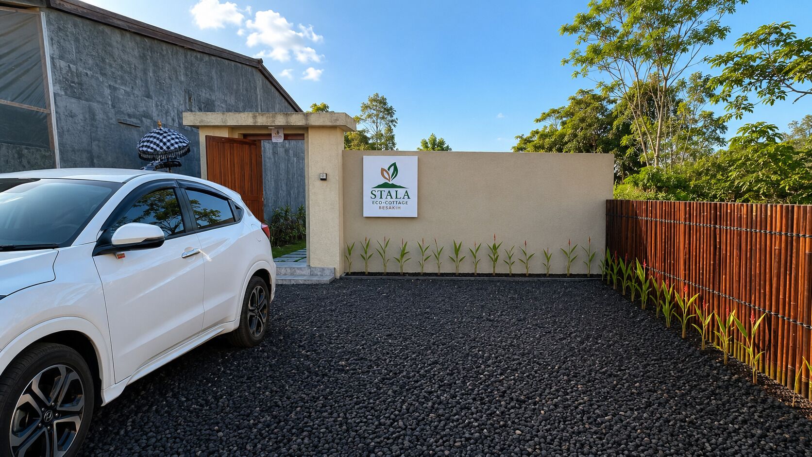 A white car parked in front of a building with a sign reading 'STALA ECO COTTAGE BESAKIH.'