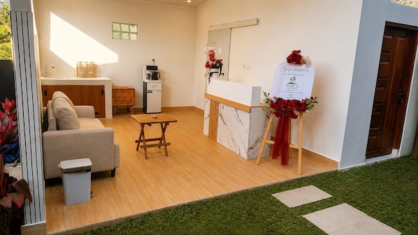 A modern interior with a sofa, coffee machine, and a reception desk with a red flower arrangement. - Stala Eco-Cottage Besakih (Karangasem)