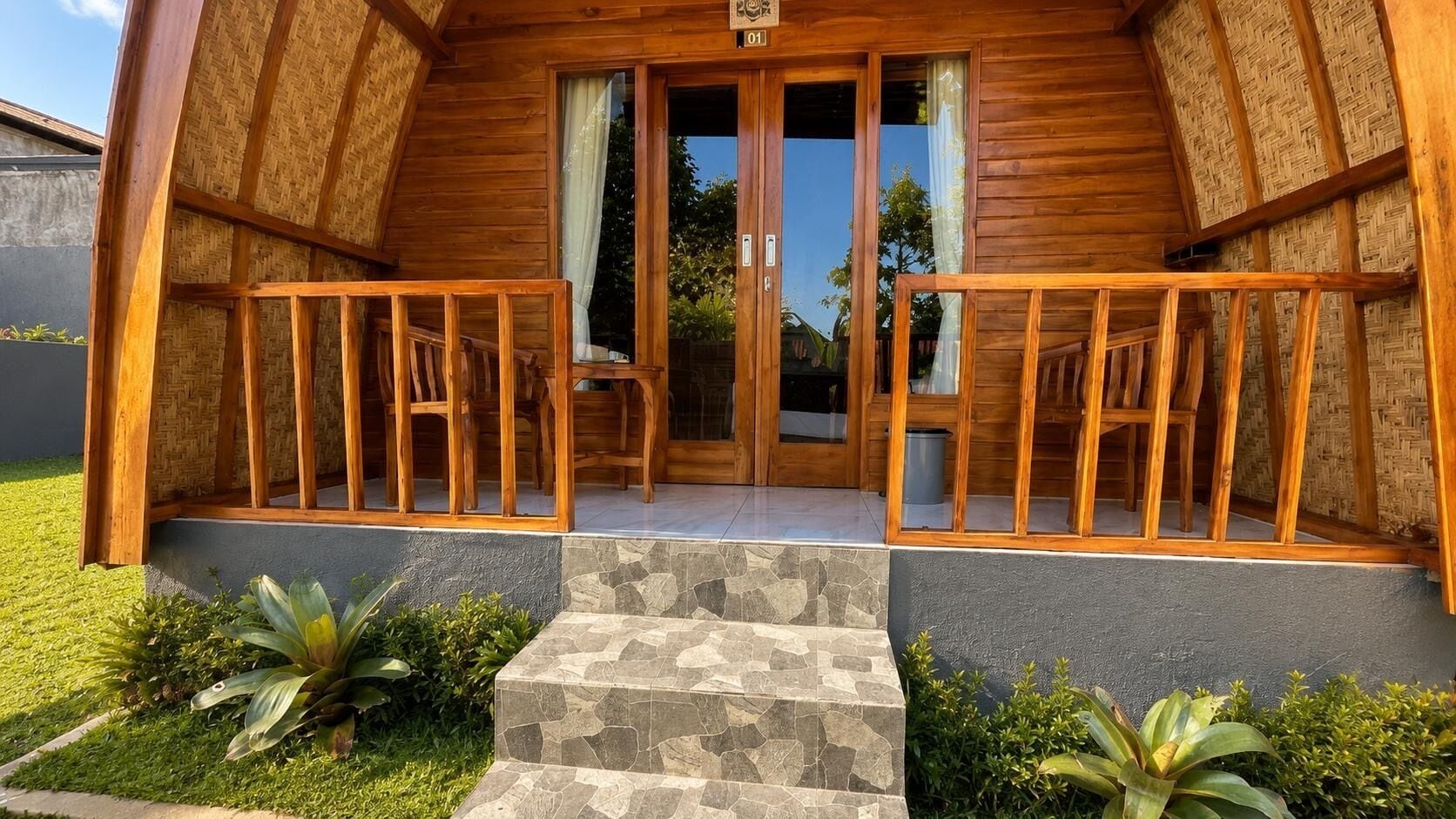 A wooden cabin with a stone staircase leading to a wooden porch with chairs.