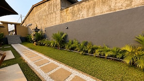 A pathway leading to a building with a modern design, a small garden area with palm trees, and a clear sky. - Stala Eco-Cottage Besakih (Karangasem)