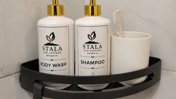 Ein Badezimmerregal mit zwei Flaschen Stala Körperwaschmittel und Shampoo sowie einer weißen Tasse.
