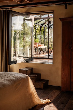 Ein Schlafzimmer mit großem Fenster, einem Bett und einer Holztreppe.
