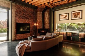 Ein modernes Wohnzimmer mit Ziegelwand, Kamin, einer Couch und gerahmten Bildern an der Wand.