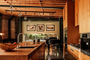 A modern kitchen with a wooden island, a built-in stove, and a large window overlooking greenery. - Luxury 3BR Ocean View Home with Pool -  Featured in The New York Times! (Los Angeles)