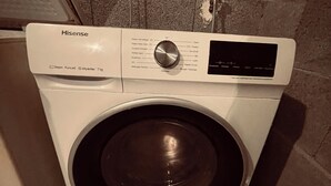 A Hisense washing machine with a control panel and a stainless steel door.