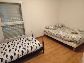 Un dormitorio con dos camas, una con colcha estampada y la otra de color liso.