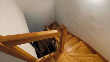 A wooden staircase with a handrail and a light fixture on the wall.