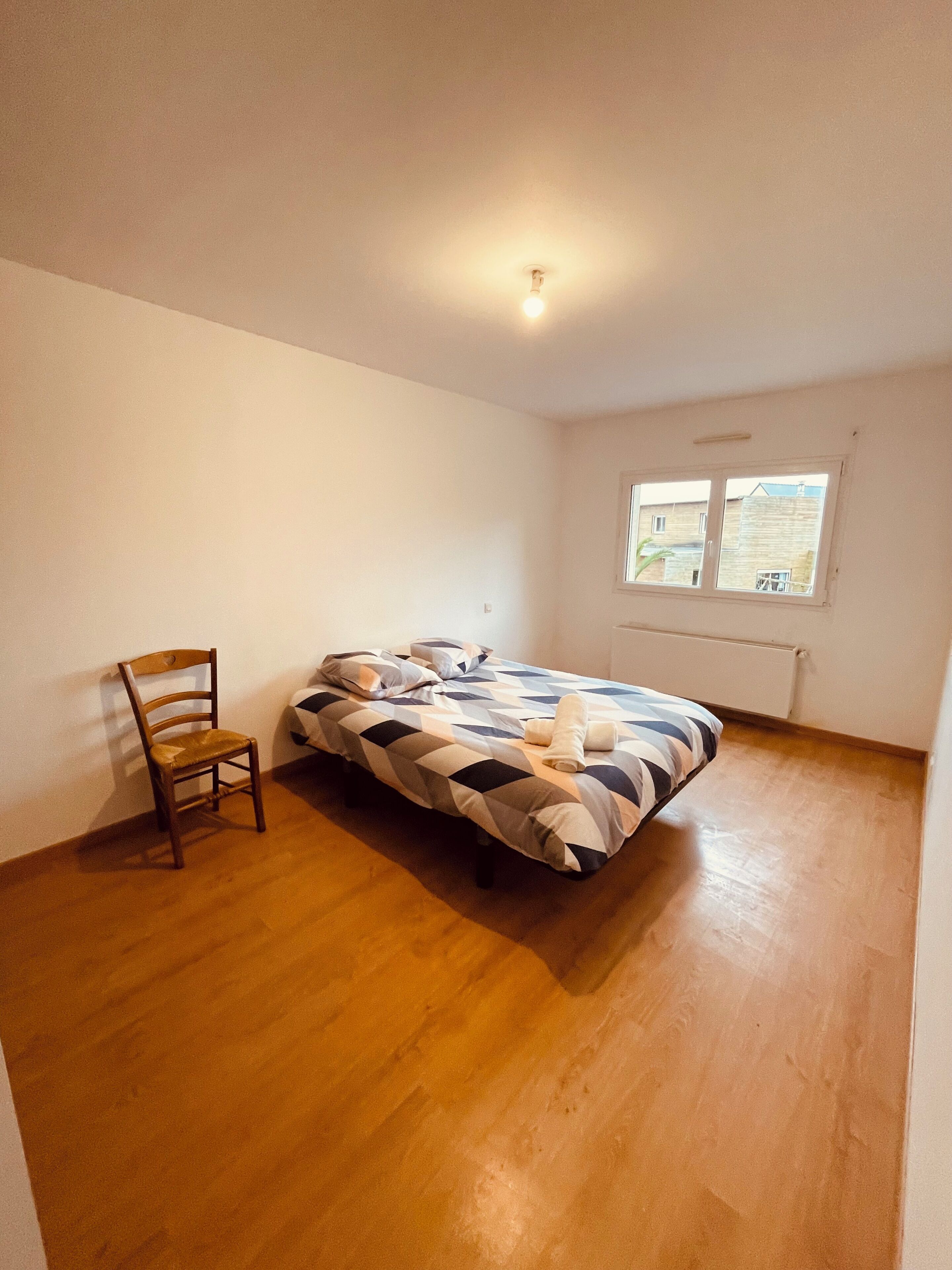A bedroom with a bed, a chair, and a window.