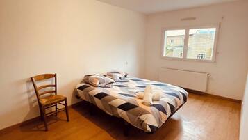 A bedroom with a bed, a chair, and a window.