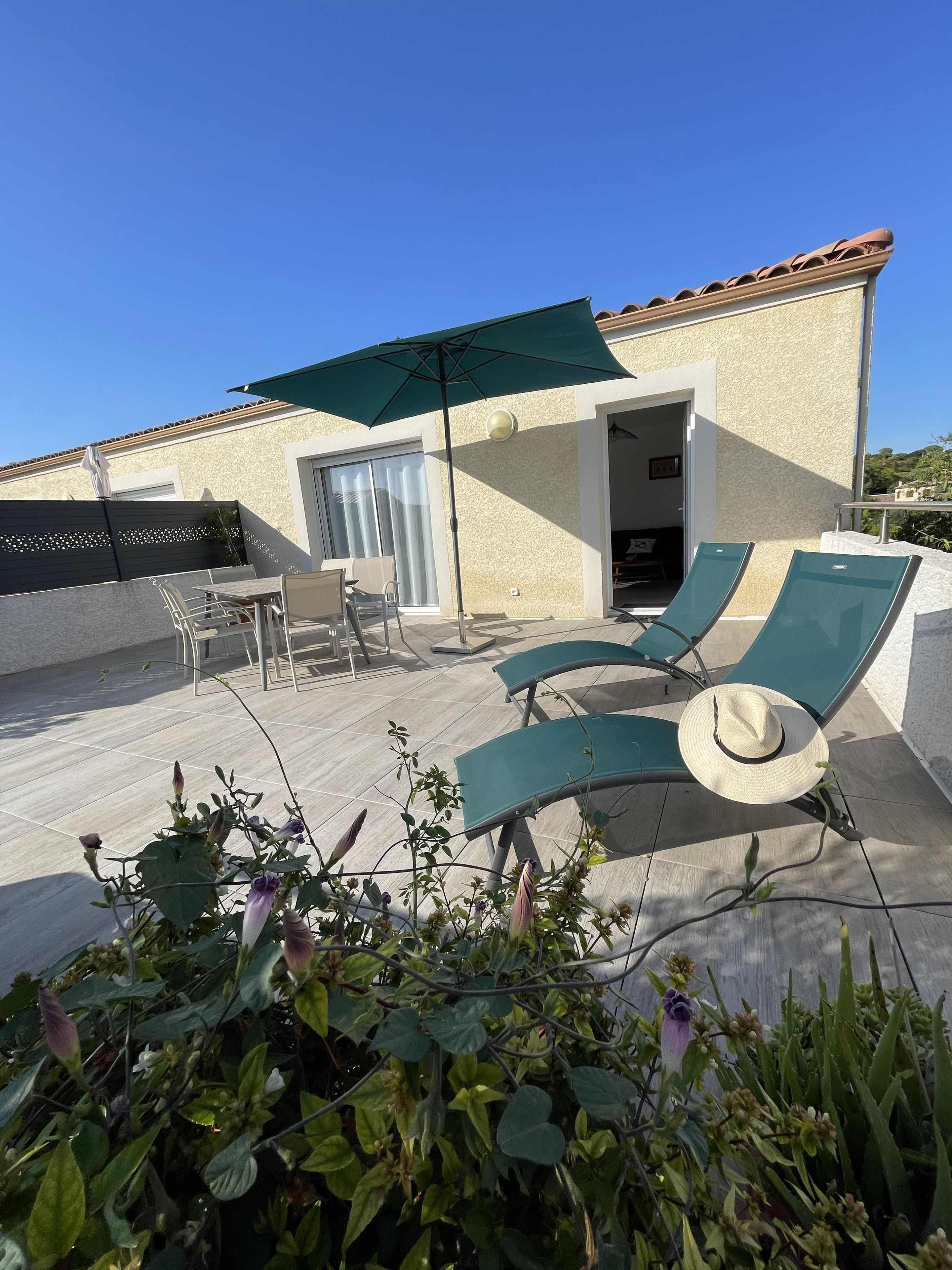 Terraza en la azotea con sillones, una mesa y una sombrilla.