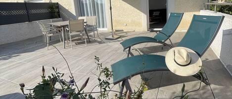 Terraza en la azotea con sillones, una mesa y una sombrilla.