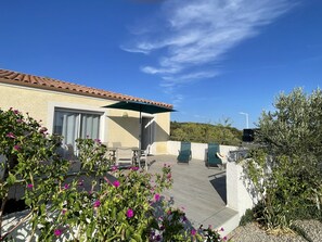 A patio with outdoor furniture, a covered seating area, and a view of a hilly landscape. - L'Olivier – A quiet, air-conditioned vacation rental in a traditional village near Pézenas (Neffiès)