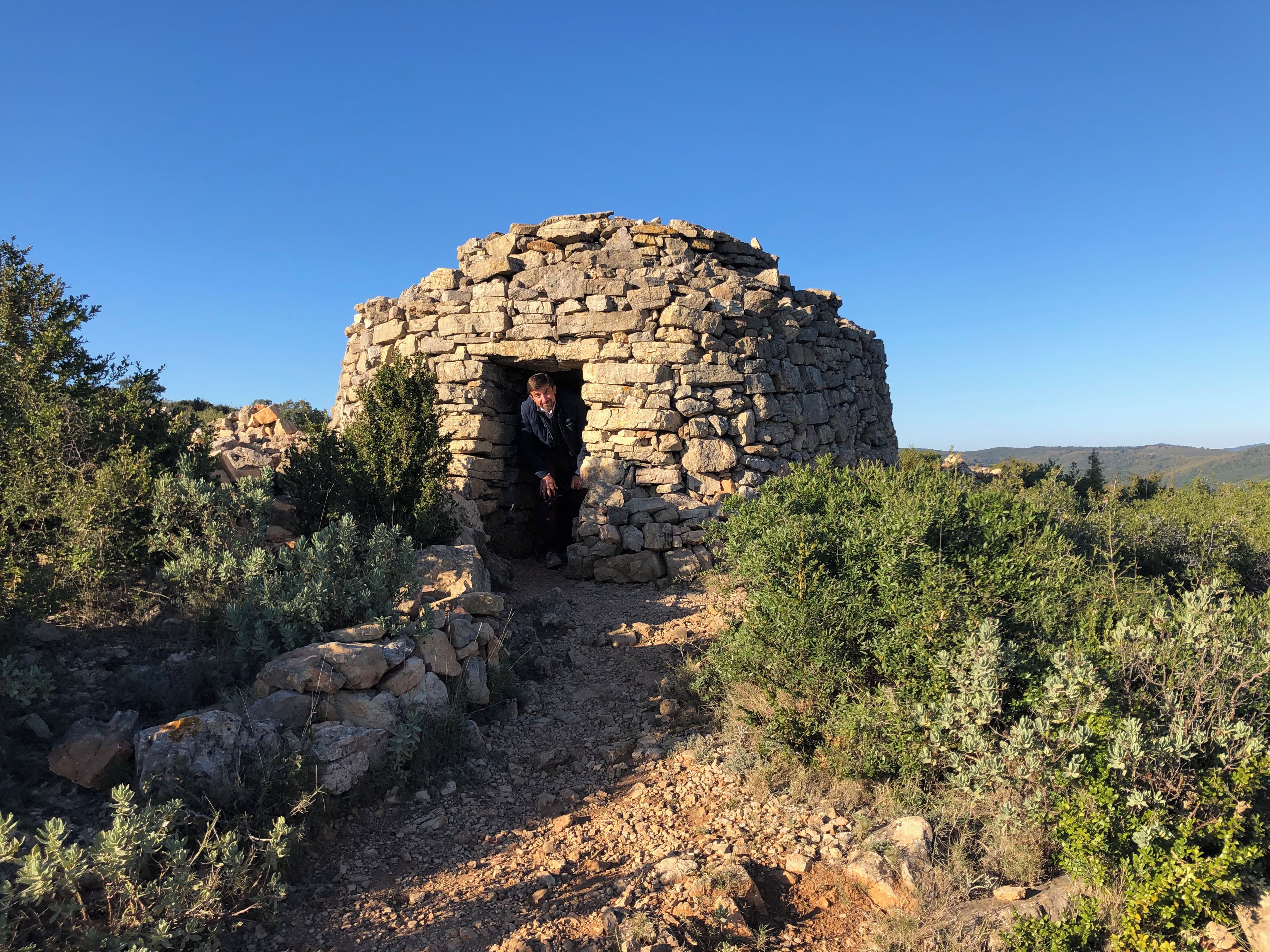 A stone structure with a person inside, surrounded by vegetation.