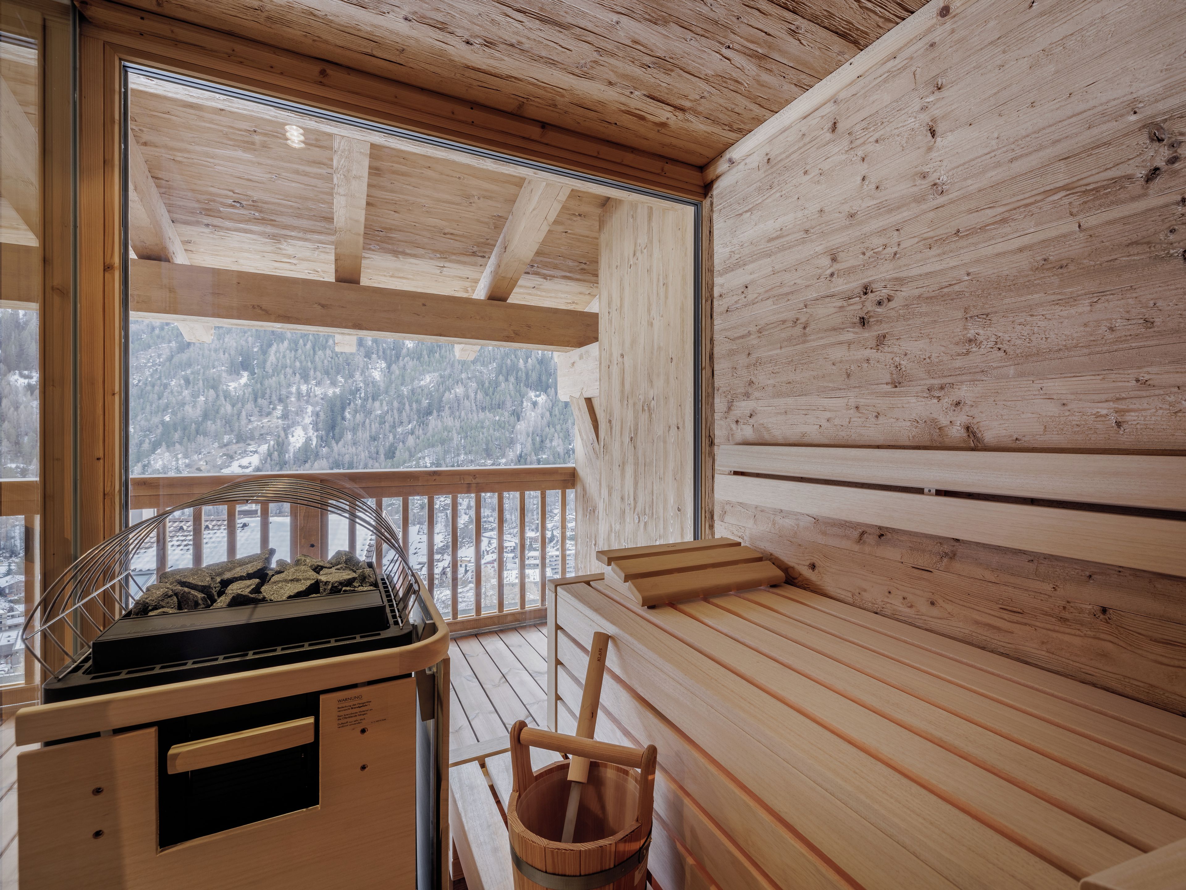 En træhytte med balkon, sauna og udsigt til sneklædte bjerge.