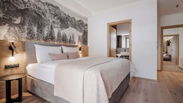 Un dormitorio con una cama grande, una mesita de noche, una lámpara de pared y un mural con un paisaje de montaña.
