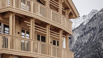 Ein mehrstöckiges Holzhaus mit Balkonen, einem Steinfundament und einer Bergkulisse.