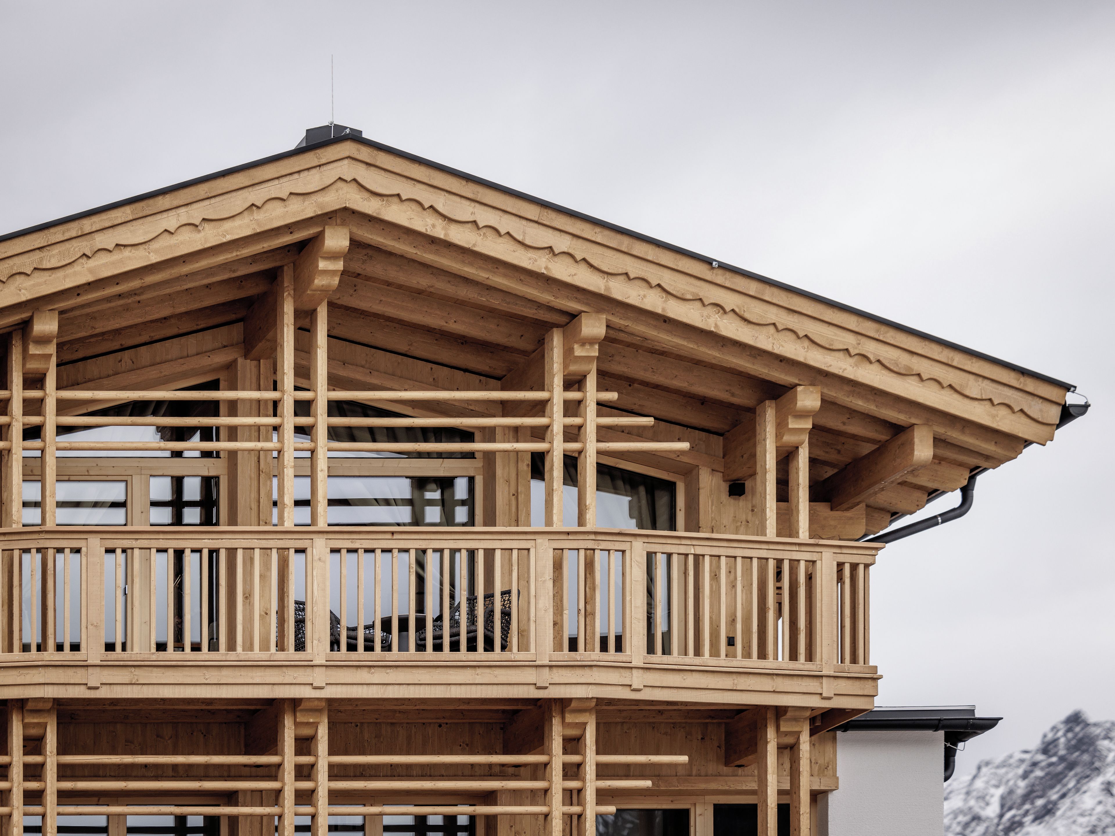 Eine Holzhütte mit Balkon, großen Fenstern und einer Bergkulisse.