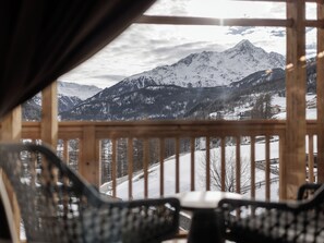 A view from a wooden balcony with a mountain landscape.