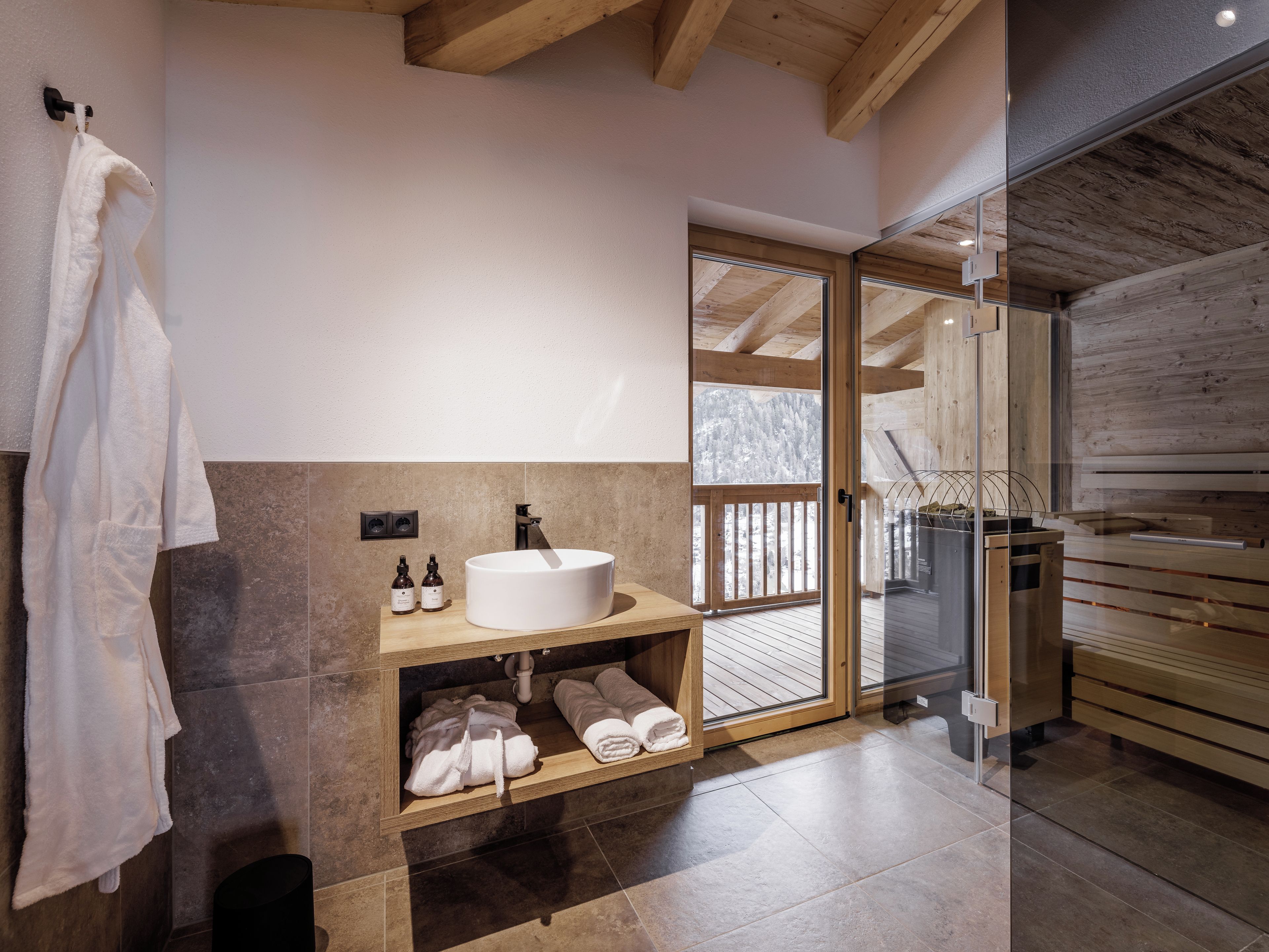 Ein modernes Badezimmer mit einem großen Waschbecken, Holzregalen und einer Glastür, die auf einen Balkon führt.
